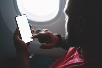 Back view of young man flight passenger connecting to wireless internet on board while sitting next to aircraft cabin window. Mock up blank screen for your content website, Airplane Offline mode