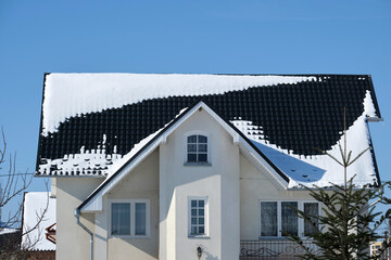 Closeup of house roof top covered with snow in cold winter. Tiled covering of building in...