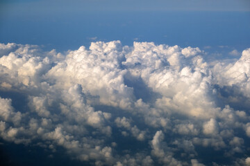 Cloudy sky, from airplane window point of view. View from above at high altitude of dense puffy...