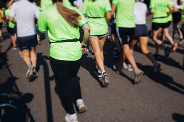 Marathon runners crowd, sportsmen participants start running the half-marathon in the city streets, crowd of sportswomen joggers in motion, group athletes outdoor training competition in a summer day