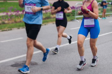 Marathon runners crowd, sportsmen participants start running the half-marathon in the city streets, crowd of sportswomen joggers in motion, group athletes outdoor training competition in a summer day
