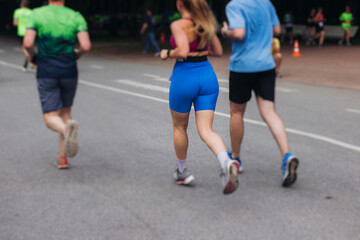 Marathon runners crowd, sportsmen participants start running the half-marathon in the city streets, crowd of sportswomen joggers in motion, group athletes outdoor training competition in a summer day