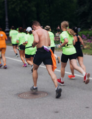 Marathon runners crowd, sportsmen participants start running the half-marathon in the city streets, crowd of sportswomen joggers in motion, group athletes outdoor training competition in a summer day