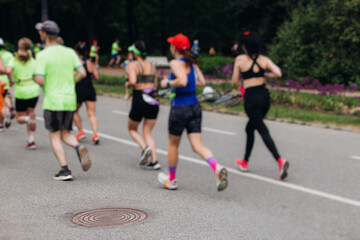 Marathon runners crowd, sportsmen participants start running the half-marathon in the city streets, crowd of sportswomen joggers in motion, group athletes outdoor training competition in a summer day