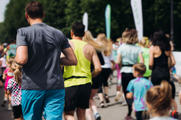 Marathon runners crowd, sportsmen participants start running the half-marathon in the city streets, crowd of sportswomen joggers in motion, group athletes outdoor training competition in a summer day