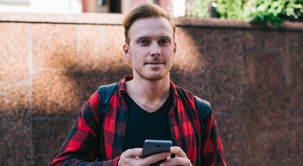 Trendy guy browsing smartphone on street