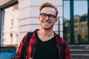 Cheerful guy with smartphone and hot beverage on street