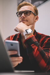 Thoughtful freelancer with smartphone in cafe