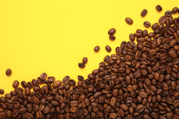 Black coffee beans on yellow background. Space for text