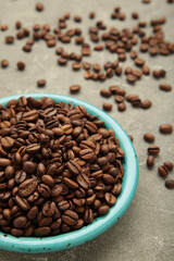 Coffee beans on plate on grey background. Vertical photo