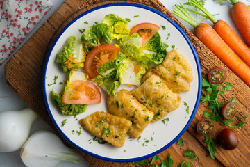 Tempura hake pieces with salad. Top view table with  decoration.