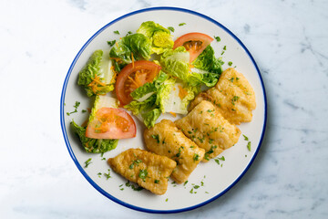 Tempura hake pieces with salad. Top view table with  decoration.