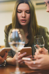 Charming female bloggers spending time togetherness for creating content text for own web pages resting with white wine in cafe interior, attractive women updating profile in social networks