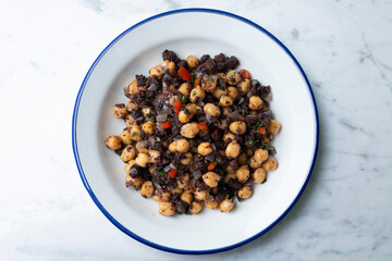 Sautéed chickpeas with black pudding and vegetables. Top view table with  decoration.