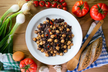 Sautéed chickpeas with black pudding and vegetables. Top view table with  decoration.