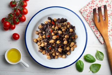 Sautéed chickpeas with black pudding and vegetables. Top view table with  decoration.