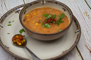 Vegan amaranth and corn soup served in a stylish bowl and platter on wooden table