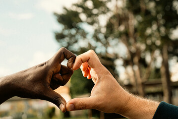 Unity and diversity: two different hands forming a heart shape outdoors