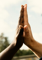 Diverse friendship celebrated through a high five gesture outdoors