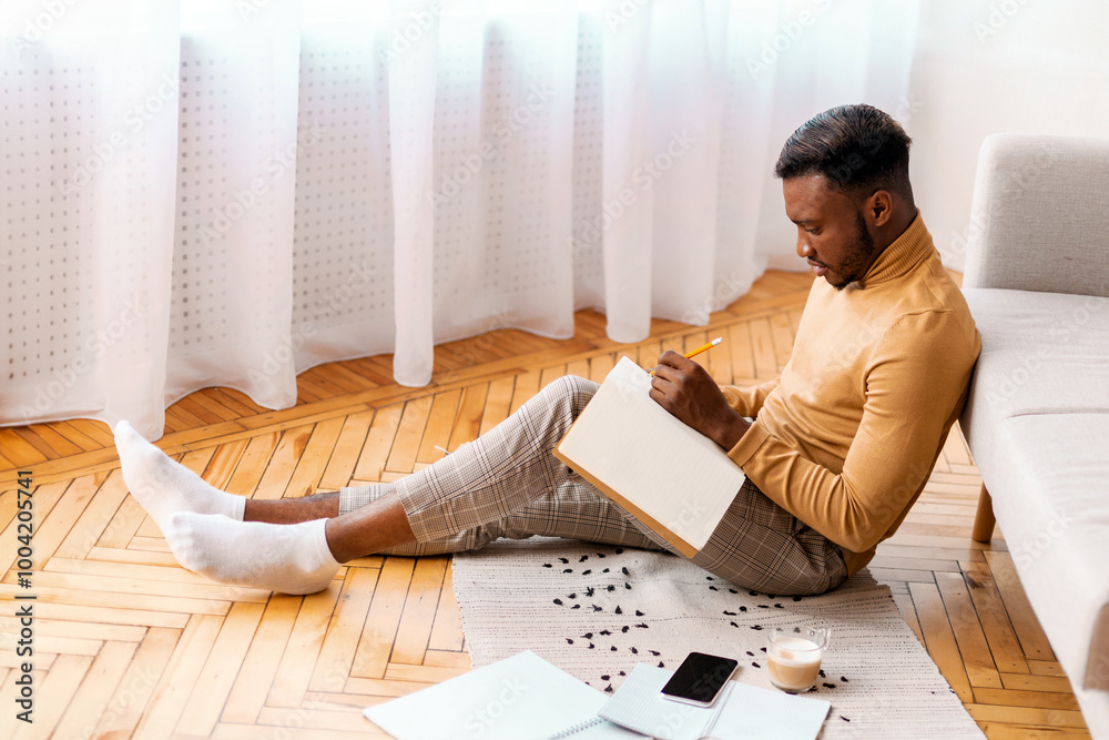 Aufkleber afro student guy taking notes preparing for lecture or exam studying sitting on floor at home. selec
