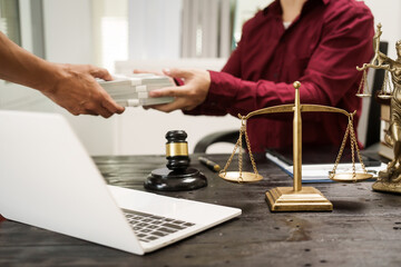 A male lawyer works at his desk, receiving cash from a client while considering the case. He focuses on law, justice, fairness, and the observance of legal rules and conventions in the system