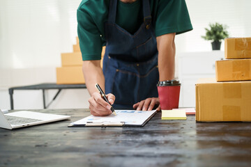 A man is working at his desk, preparing parcel boxes for shipment. He checks and packs items carefully, using shockproof materials, and attaches labels before sending them to customers via EMS.