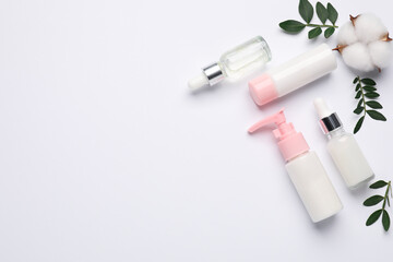 Naklejka premium Different cosmetic products, cotton flower and leaves on white background, flat lay. Space for text