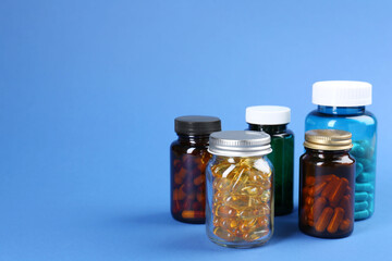 Pharmacist. Different pills in plastic bottles on blue background, space for text