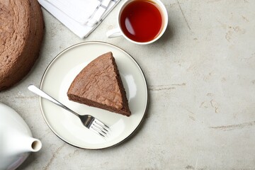 Piece of tasty chocolate sponge cake served on light table, flat lay. Space for text