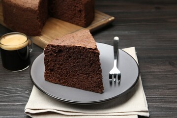 Piece of tasty chocolate sponge cake served on wooden table, closeup