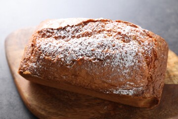 Tasty sponge cake with powdered sugar on grey table, closeup