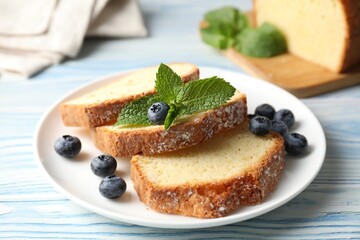 Freshly baked sponge cake, blueberries and mint on light blue wooden table, closeup