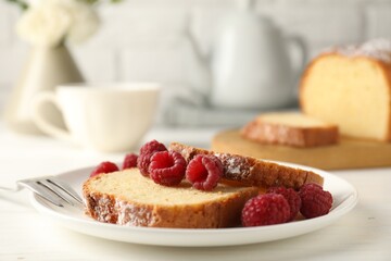 Freshly baked sponge cake and raspberries on white wooden table, closeup