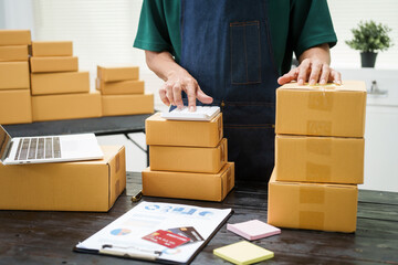 A man is working at his desk, preparing parcel boxes for shipment. He checks and packs items carefully, using shockproof materials, and attaches labels before sending them to customers via EMS.