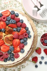 Delicious chocolate sponge cake with berries served on white wooden table, top view