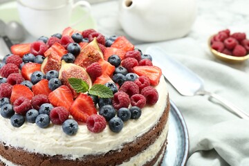 Delicious chocolate sponge cake with berries served on white table, closeup