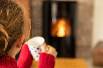 Woman warming herself in front of a pellet stove