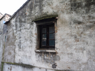 Old weathered wall with a small rustic window in a historic building.