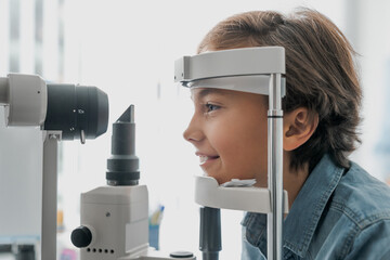 Side view shot of boy checking vision with tonometer at eye clinic