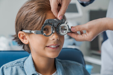 Young boy smiling while undergoing eye test with phoropter