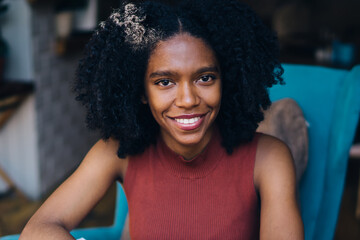 Portrait of cheerful talented female writer of children books sitting at table with laptop device and feeling good from time for creating positive content text, happy hipster girl with netbook