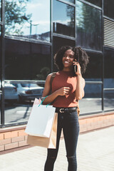 Cheerful hipster girl holding packages bags with purchases after shopping and calling for boast of...