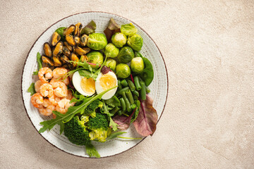 Shrimp and mussels cooked in coconut oil, served with greens, brussels sprouts, broccoli and eggs. Keto diet.