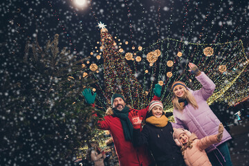 Photo of charming excited wife husband school girl boy waving palms enjoying xmas walk cuddling outdoors city fair