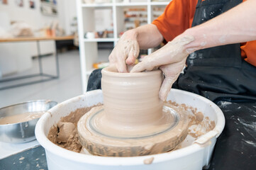 Close-up of a potter's hands making a ceramic vase on a potter's wheel. 