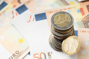 Stack of coins on euro banknotes, closeup. Space for text