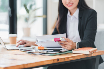 professional woman is organizing documents at desk, surrounded by paperwork and laptop, showcasing...