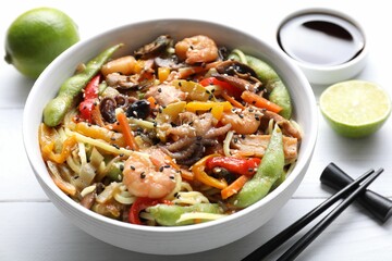 Stir-fry noodles with sea food served on white wooden table, closeup