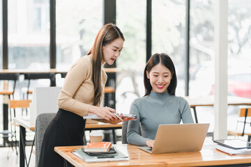 Collaborative women working together in modern office environment, sharing ideas and discussing projects while using laptop. Their teamwork reflects positive and productive atmosphere.