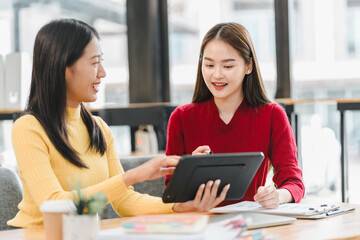 Collaborative women discussing ideas while using tablet in modern workspace. Their expressions reflect engagement and creativity as they share insights.